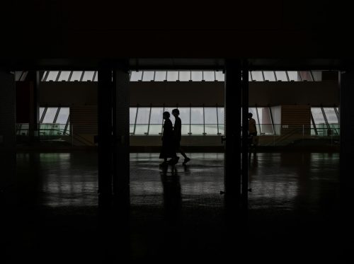 Silhouette of people walking through a modern hallway with large windows in Shanghai, China.